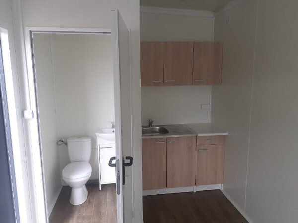 Intérieur du container, présentant la kitchenette et le WC compact.